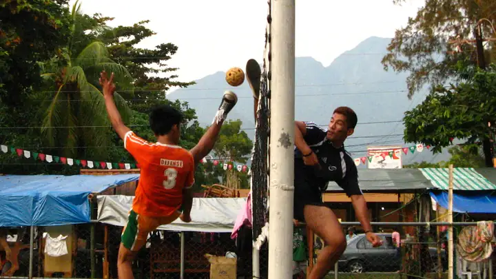Two sepak takraw players leap at the net for the rattan ball at Visayas State University, Philippines